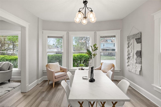 1702 Logan Ave, Des Moines, IA 50316 - dining space featuring light wood-style floors, baseboards, a healthy amount of sunlight, and an inviting chandelier