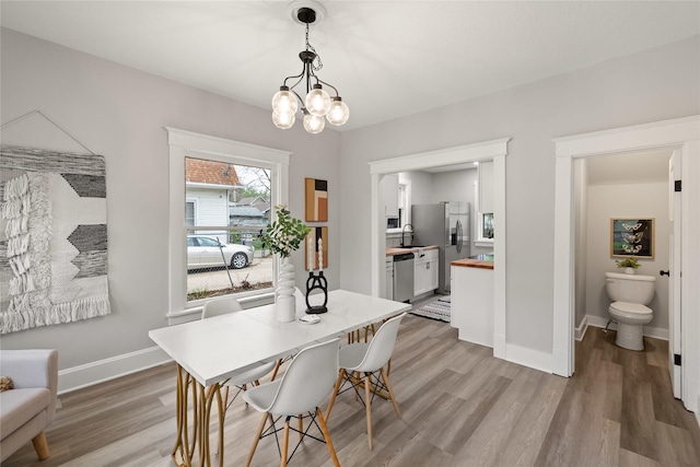 1702 Logan Ave, Des Moines, IA 50316 - dining room with baseboards, an inviting chandelier, and light wood-style floors