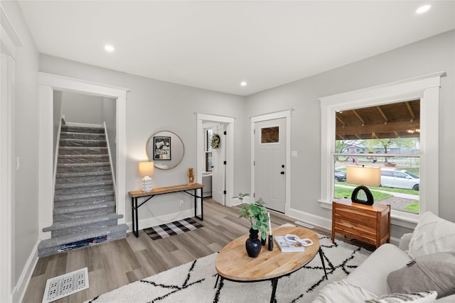 1702 Logan Ave, Des Moines, IA 50316 - living area featuring visible vents, baseboards, light wood-style floors, and stairway