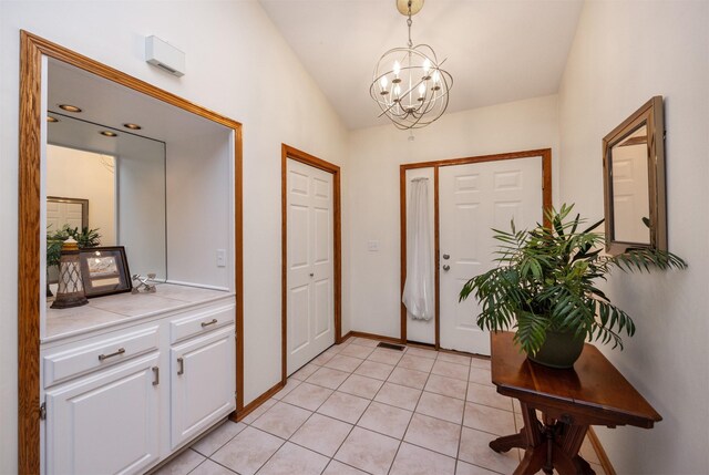 entrance foyer featuring baseboards, visible vents, an inviting chandelier, lofted ceiling, and light tile patterned flooring