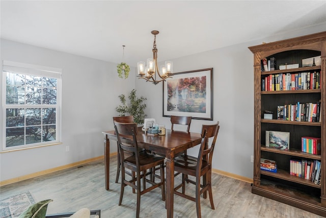5558 Boston Ct, Johnston, IA 50131 - dining space with light wood-style flooring, a chandelier, and baseboards