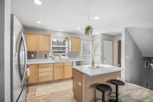 5558 Boston Ct, Johnston, IA 50131 - kitchen featuring appliances with stainless steel finishes, light brown cabinetry, a sink, light wood-style flooring, and decorative backsplash