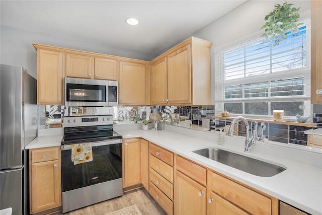 5558 Boston Ct, Johnston, IA 50131 - kitchen with appliances with stainless steel finishes, a sink, light brown cabinets, light wood-style flooring, and tasteful backsplash