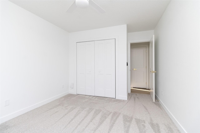 unfurnished bedroom with a closet, carpet flooring, baseboards, and ceiling fan