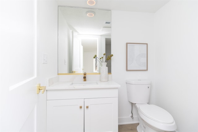 half bathroom featuring visible vents, baseboards, vanity, and toilet