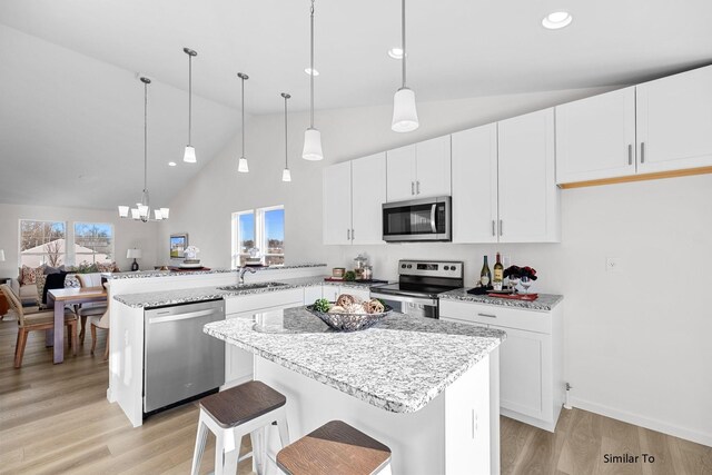 kitchen with stainless steel appliances, a peninsula, a sink, light wood-type flooring, and high vaulted ceiling