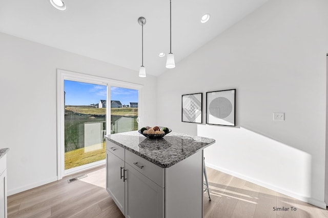 kitchen with recessed lighting, stone counters, a center island, vaulted ceiling, and pendant lighting