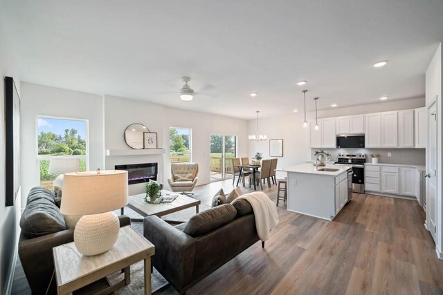 125 NW Rolling Cir, Waukee, IA 50263 - living room featuring a ceiling fan, wood finished floors, a glass covered fireplace, a chandelier, and recessed lighting