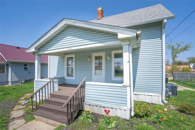 view of front of property featuring central air condition unit, a porch, and a chimney