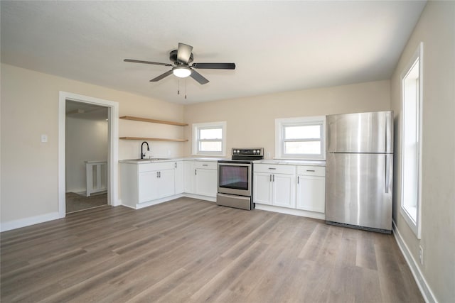 kitchen with white cabinets, open shelves, light countertops, light wood-style flooring, and appliances with stainless steel finishes
