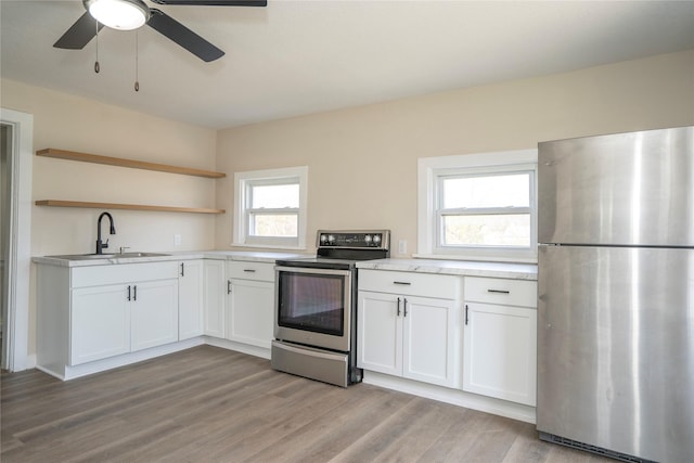 kitchen with open shelves, white cabinets, a sink, and appliances with stainless steel finishes