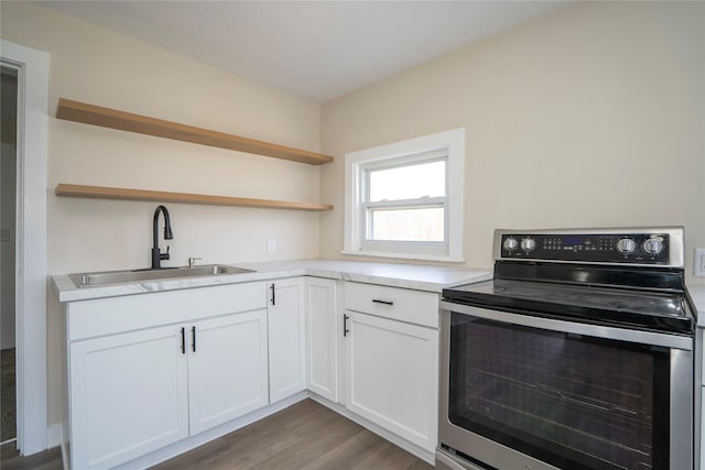 kitchen featuring open shelves, electric stove, a sink, light countertops, and white cabinets