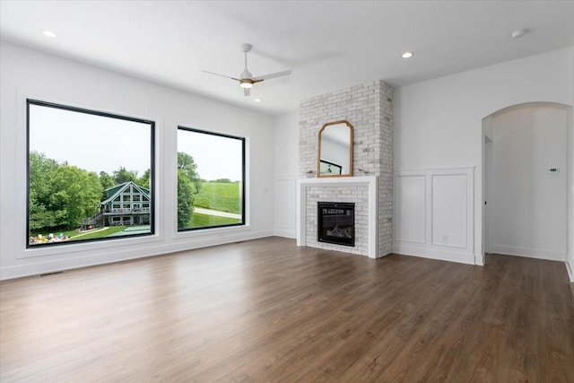 1296 Bee Tree Ln, Ellston, IA 50074 - unfurnished living room with ceiling fan, wood finished floors, a fireplace, a decorative wall, and arched walkways