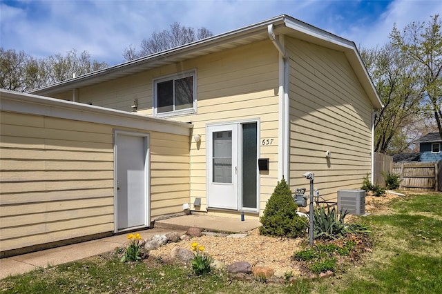 rear view of property with central air condition unit and fence