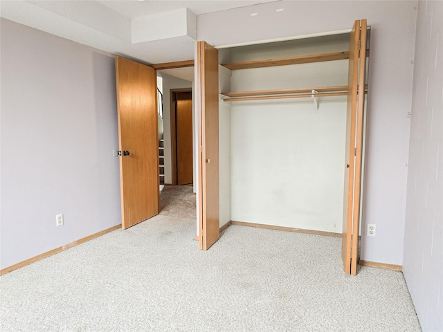 unfurnished bedroom featuring baseboards, a closet, and carpet flooring