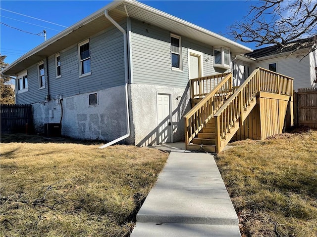 1144 Euclid Ave, Des Moines, IA 50313 - back of house with stucco siding, fence, stairs, central AC unit, and a lawn