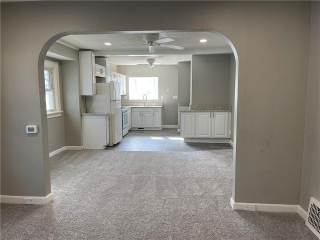 1144 Euclid Ave, Des Moines, IA 50313 - kitchen featuring white cabinetry, light carpet, arched walkways, and ceiling fan