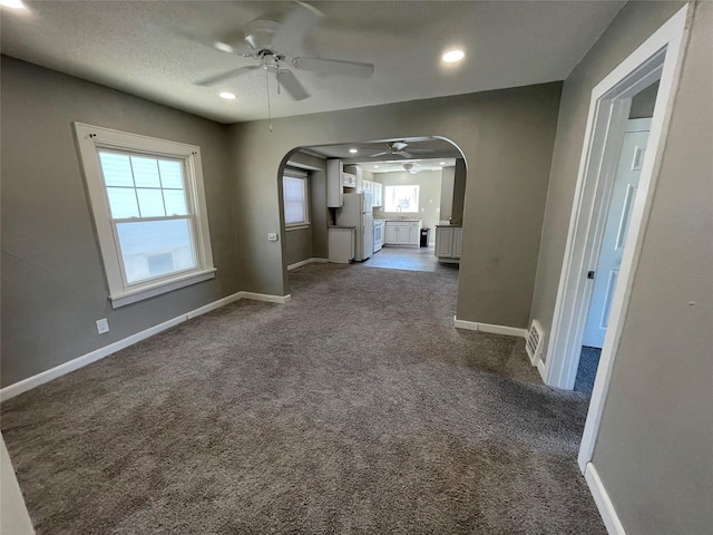 1144 Euclid Ave, Des Moines, IA 50313 - unfurnished living room featuring baseboards, ceiling fan, recessed lighting, arched walkways, and dark carpet