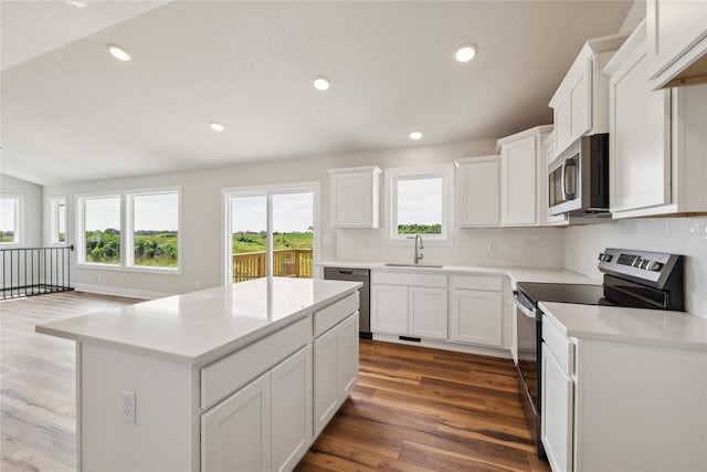 1430 Werthman Dr, Waukee, IA 50263 - kitchen with stainless steel appliances, wood finished floors, decorative backsplash, a center island, and white cabinets