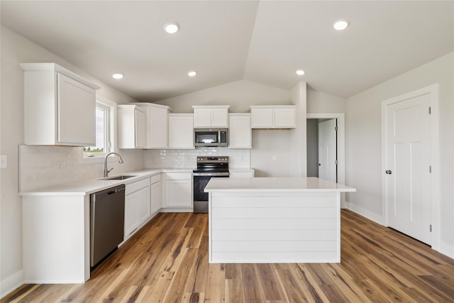 1430 Werthman Dr, Waukee, IA 50263 - kitchen featuring appliances with stainless steel finishes, white cabinetry, a center island, backsplash, and vaulted ceiling