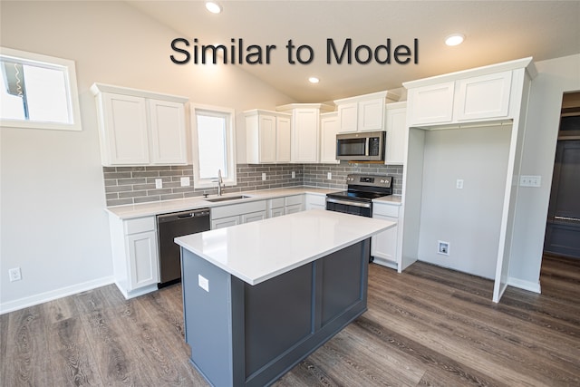kitchen featuring appliances with stainless steel finishes, a sink, dark wood-style flooring, white cabinets, and lofted ceiling
