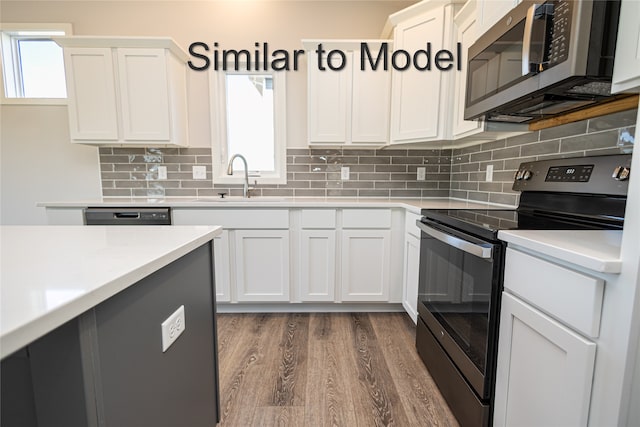kitchen with stainless steel appliances, a sink, dark wood-style flooring, light countertops, and white cabinetry