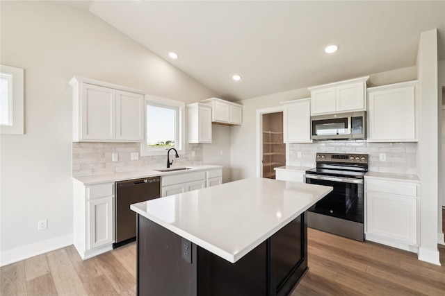 1440 Werthman Dr, Waukee, IA 50263 - kitchen featuring appliances with stainless steel finishes, vaulted ceiling, white cabinets, light countertops, and recessed lighting
