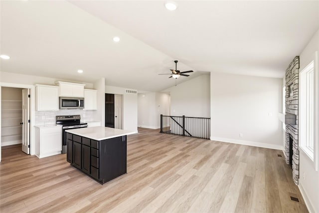 1440 Werthman Dr, Waukee, IA 50263 - kitchen featuring appliances with stainless steel finishes, light countertops, ceiling fan, a kitchen island, and light wood finished floors