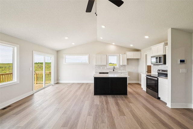 1440 Werthman Dr, Waukee, IA 50263 - kitchen with appliances with stainless steel finishes, tasteful backsplash, vaulted ceiling, light wood-style flooring, and white cabinets