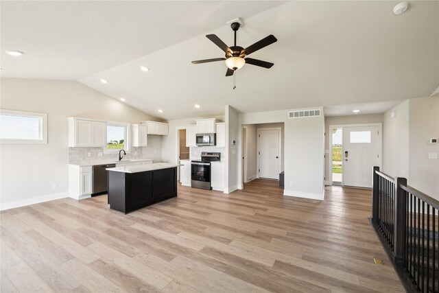 1440 Werthman Dr, Waukee, IA 50263 - kitchen with stainless steel appliances, lofted ceiling, open floor plan, white cabinetry, and backsplash