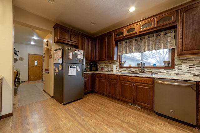 2141 320th St, Fort Dodge, IA 50501 - kitchen with light wood-style floors, a sink, backsplash, and appliances with stainless steel finishes