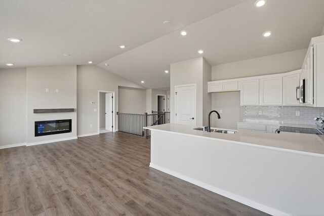 1911 20th Ave SE, Altoona, IA 50009 - kitchen featuring stove, white cabinetry, vaulted ceiling, a peninsula, and tasteful backsplash