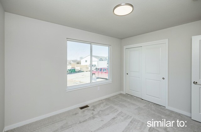16614 Walnut Meadows Dr, Urbandale, IA 50323 - unfurnished bedroom featuring a closet, baseboards, light colored carpet, and visible vents