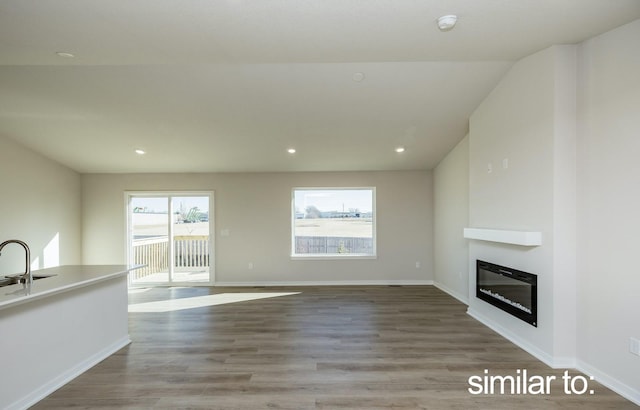 16614 Walnut Meadows Dr, Urbandale, IA 50323 - unfurnished living room with a glass covered fireplace, wood finished floors, baseboards, recessed lighting, and a sink