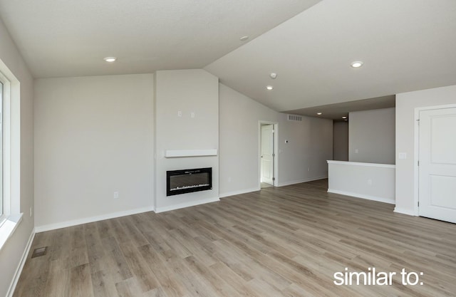 16614 Walnut Meadows Dr, Urbandale, IA 50323 - unfurnished living room with visible vents, vaulted ceiling, baseboards, light wood finished floors, and a glass covered fireplace