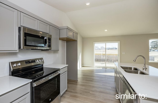16614 Walnut Meadows Dr, Urbandale, IA 50323 - kitchen featuring appliances with stainless steel finishes, a sink, light countertops, decorative backsplash, and vaulted ceiling