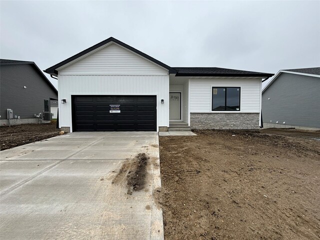 16614 Walnut Meadows Dr, Urbandale, IA 50323 - view of front of house featuring central air condition unit, concrete driveway, stone siding, and a garage