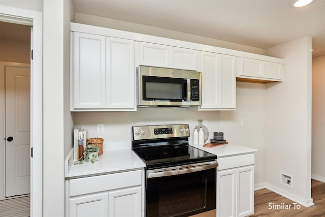 kitchen featuring light wood-type flooring, light countertops, white cabinets, baseboards, and appliances with stainless steel finishes