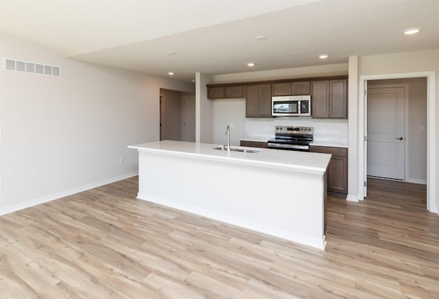6411 NE 11th Ct, Des Moines, IA 50313 - kitchen with stainless steel appliances, a sink, decorative backsplash, light wood finished floors, and recessed lighting
