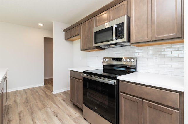 6411 NE 11th Ct, Des Moines, IA 50313 - kitchen featuring stainless steel appliances, decorative backsplash, light wood-style flooring, light countertops, and recessed lighting