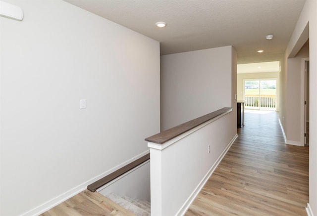 6411 NE 11th Ct, Des Moines, IA 50313 - hall with an upstairs landing, light wood-style flooring, recessed lighting, baseboards, and a textured ceiling