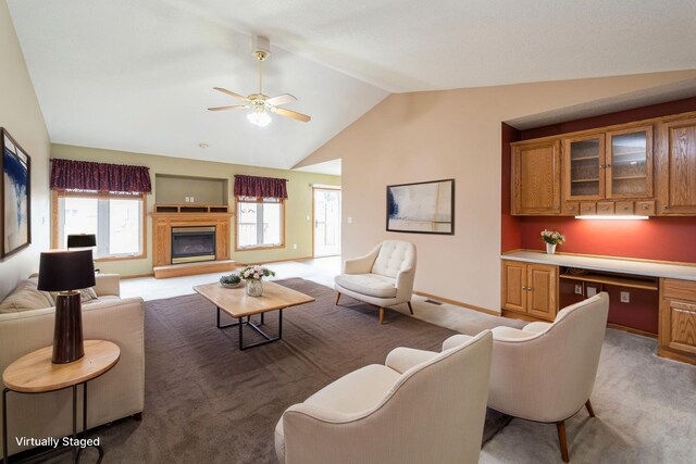 living room with built in study area, light carpet, lofted ceiling, baseboards, and ceiling fan