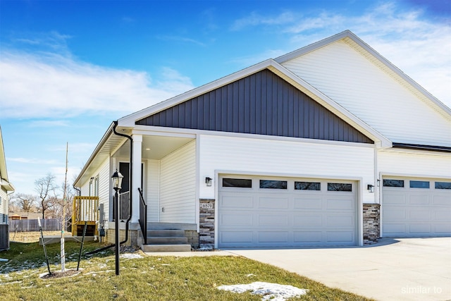 view of front of home featuring driveway, stone siding, fence, cooling unit, and a garage
