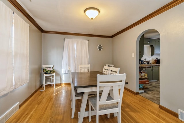 807 Virginia Ave, Des Moines, IA 50315 - dining area featuring arched walkways, baseboards, visible vents, and light wood-style floors