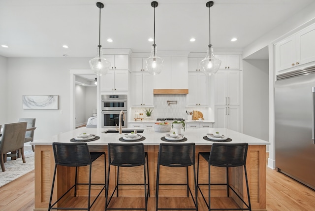 18167 Alderleaf Dr, Clive, IA 50325 - kitchen featuring appliances with stainless steel finishes, light wood-type flooring, a sink, decorative backsplash, and recessed lighting