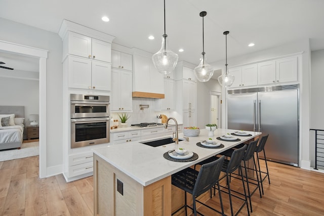 18167 Alderleaf Dr, Clive, IA 50325 - kitchen with stainless steel appliances, a sink, recessed lighting, light wood-style floors, and white cabinets