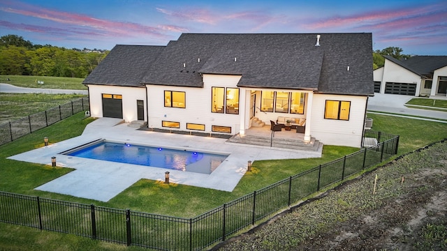 18167 Alderleaf Dr, Clive, IA 50325 - back of house at dusk with outdoor lounge area, roof with shingles, a patio area, and an attached garage