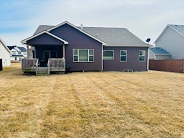 rear view of house with a lawn and fence