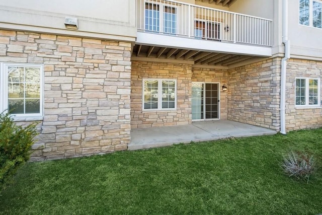 exterior space with stone siding, a balcony, stucco siding, and a patio area