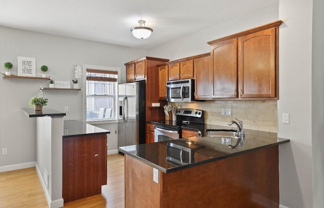 193 63rd St Unit 20107, West Des Moines, IA 50266 - kitchen with stainless steel appliances, a sink, a peninsula, decorative backsplash, and light wood-type flooring
